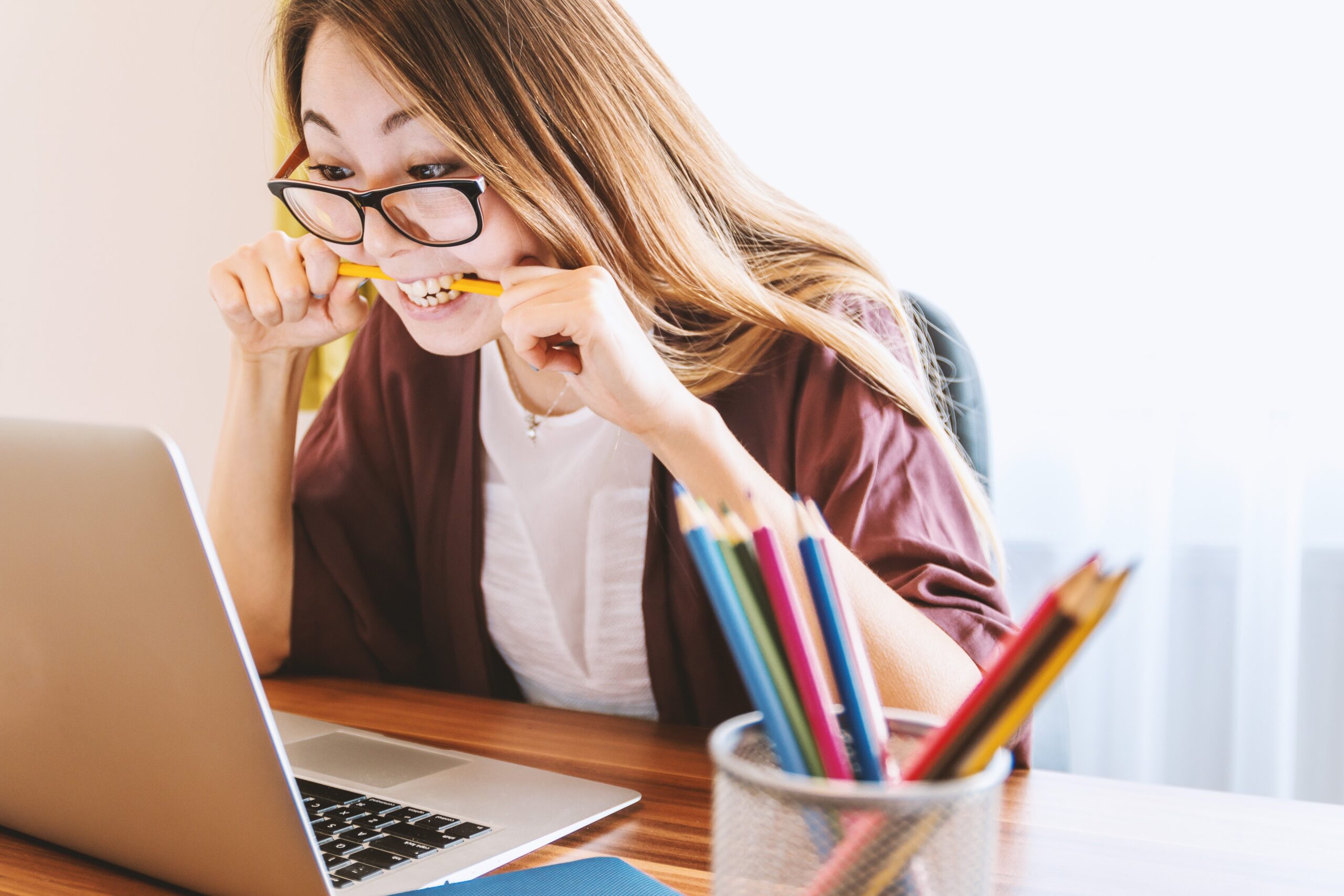 Student at laptop biting pencil